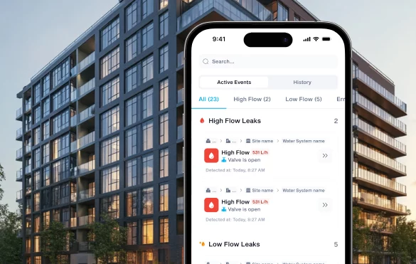Phone showing details about leaks and amounts of flow in the leaks held in front of a large building.